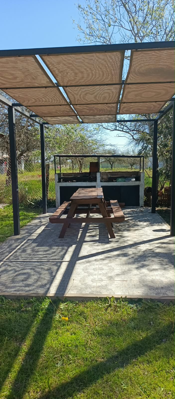 Quincho con parrilla bajo pérgola de Lo De Ely