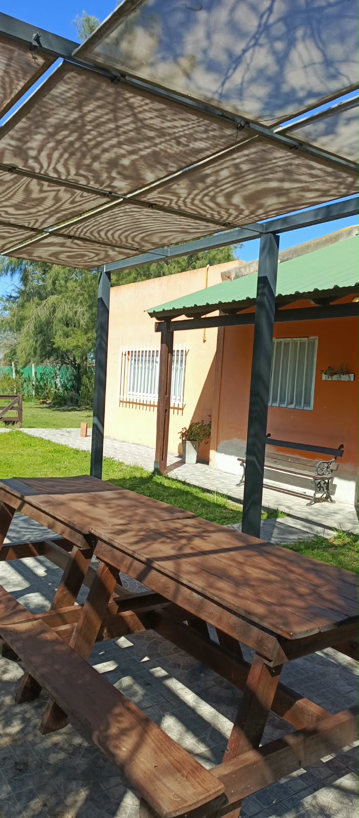 Pérgola con mesa y banco frente a la casa de Lo De Ely